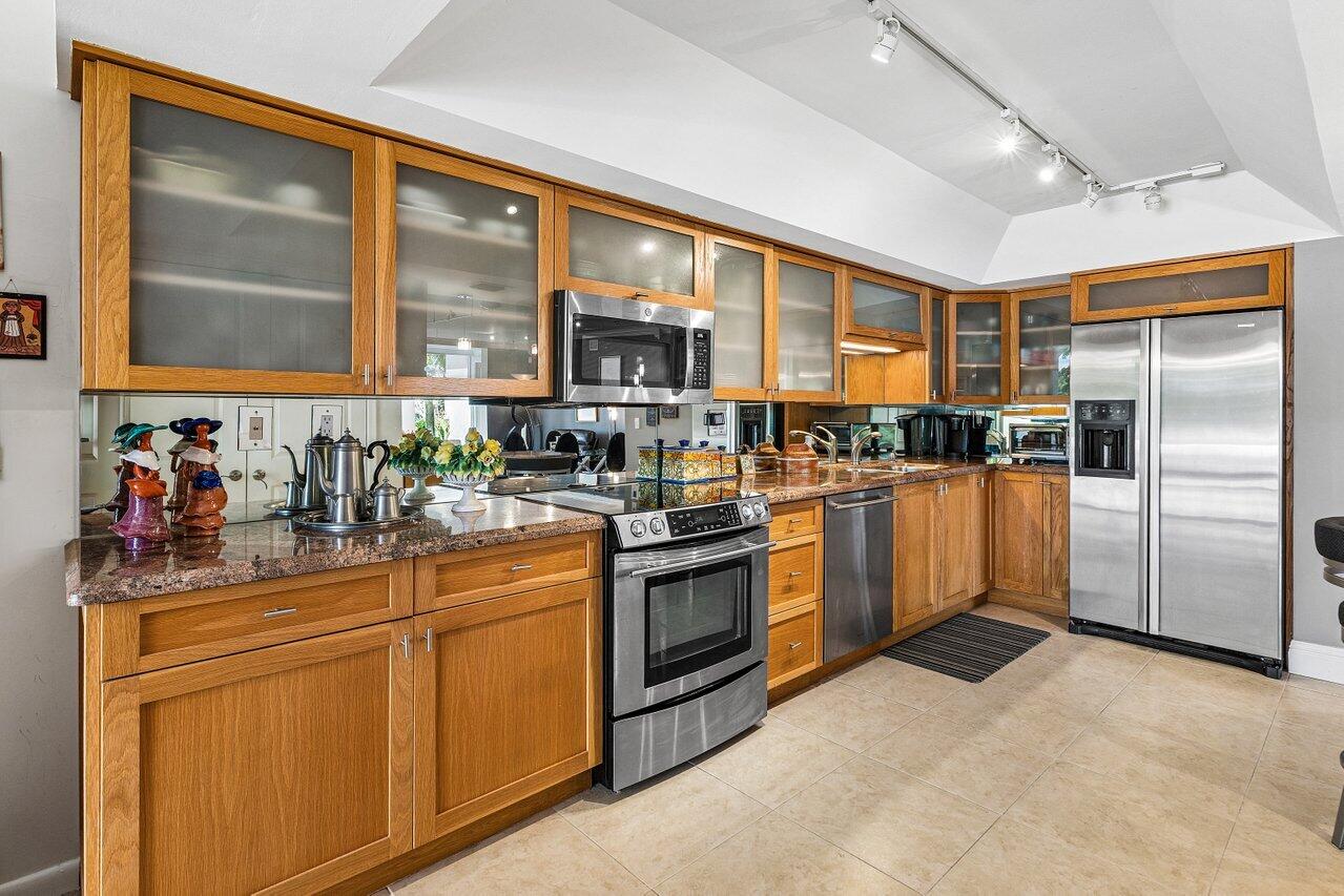 Kitchen with honey-colored wood cabinets, granite countertops, and stainless-steel appliances.