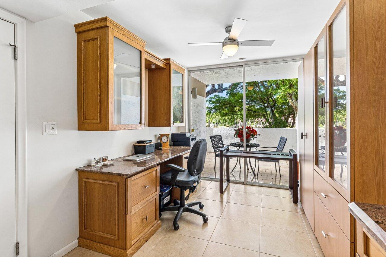 Home office with built-in wood cabinetry and sliding glass doors to a tree-lined patio.