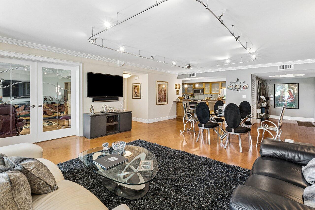 Open-plan living and dining room with hardwood floors, black rug, and kitchen beyond.
