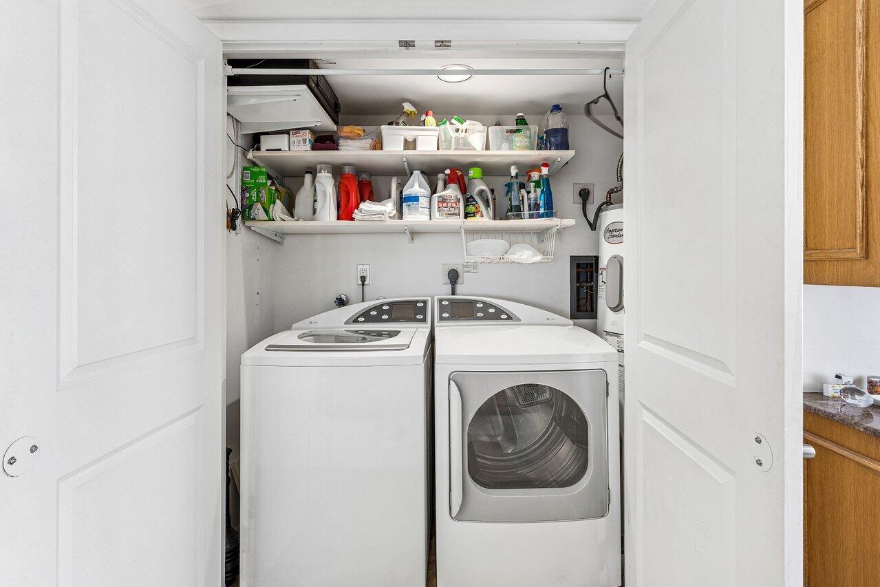 Laundry room with a washer and dryer beneath shelves of cleaning supplies.