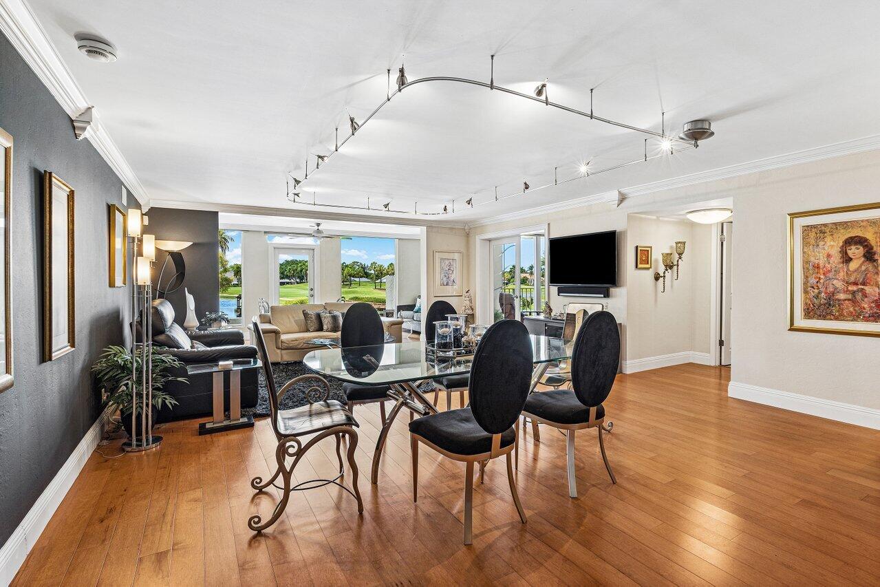 Living and dining room with hardwood floors, black dining chairs, and golf course views through the windows.