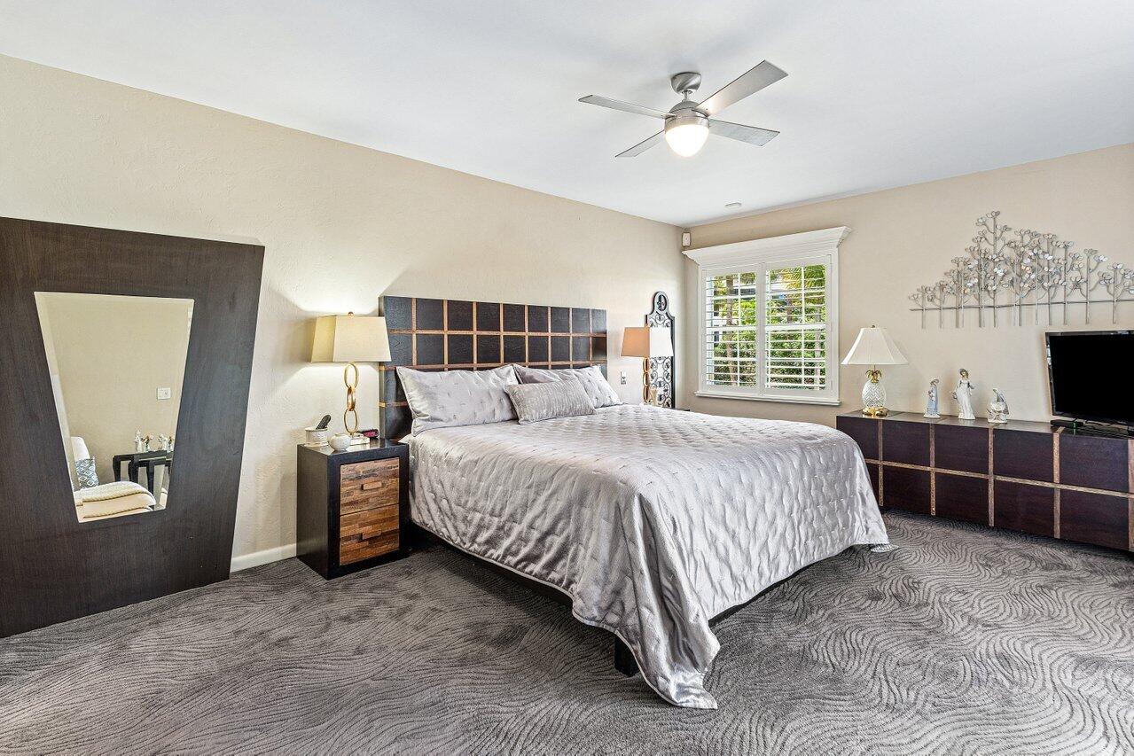 Bedroom with a large bed, dark wood furniture, patterned gray carpet, and a shuttered window.