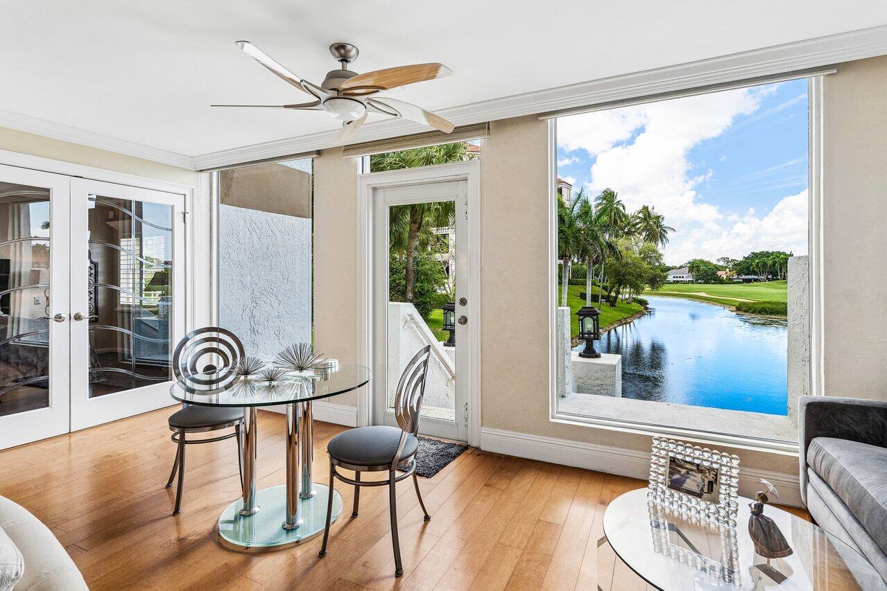 Dining area with a glass table overlooking a palm-lined canal and golf course.