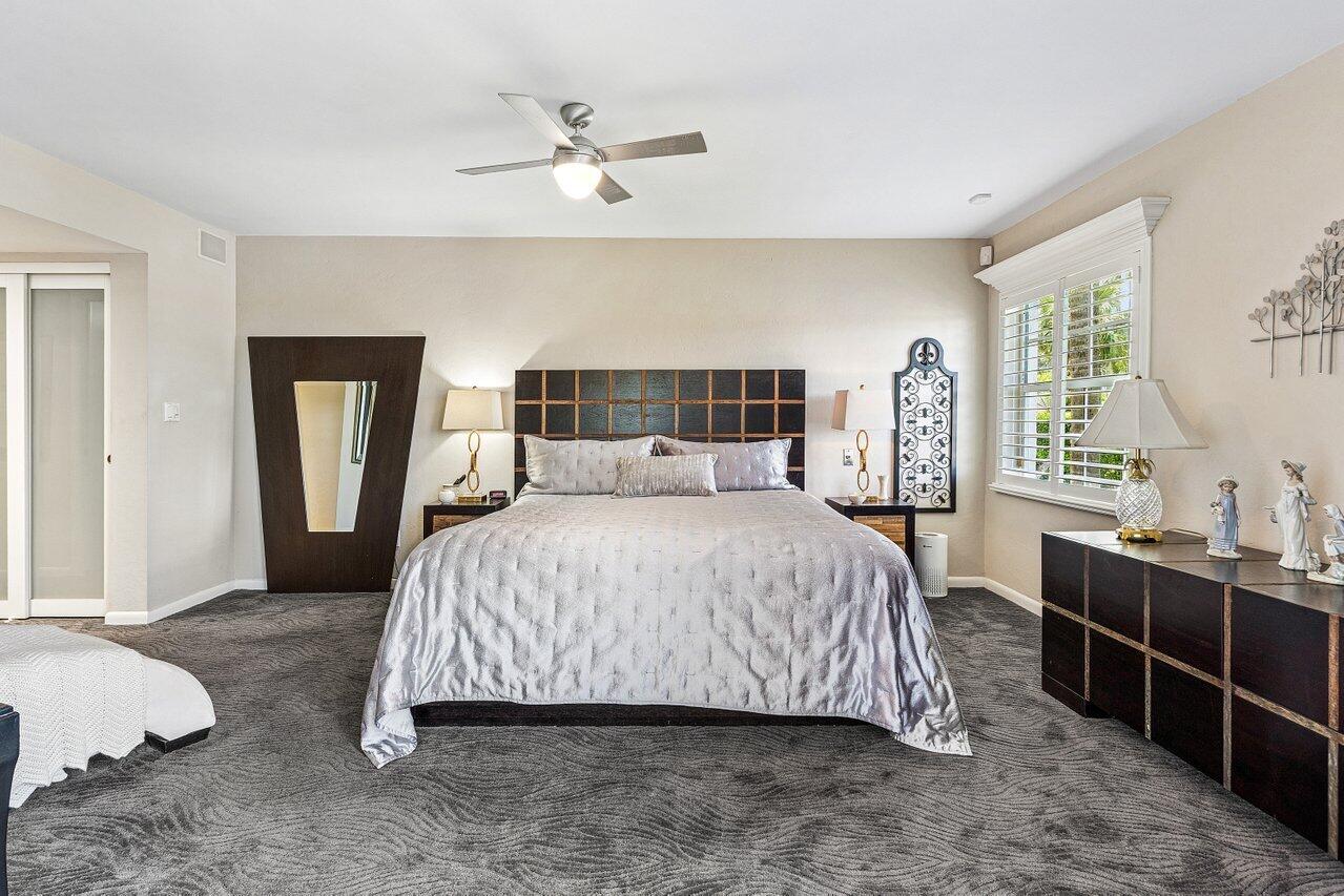 Furnished bedroom with a large bed, dark wood furniture, and plantation-shuttered window.
