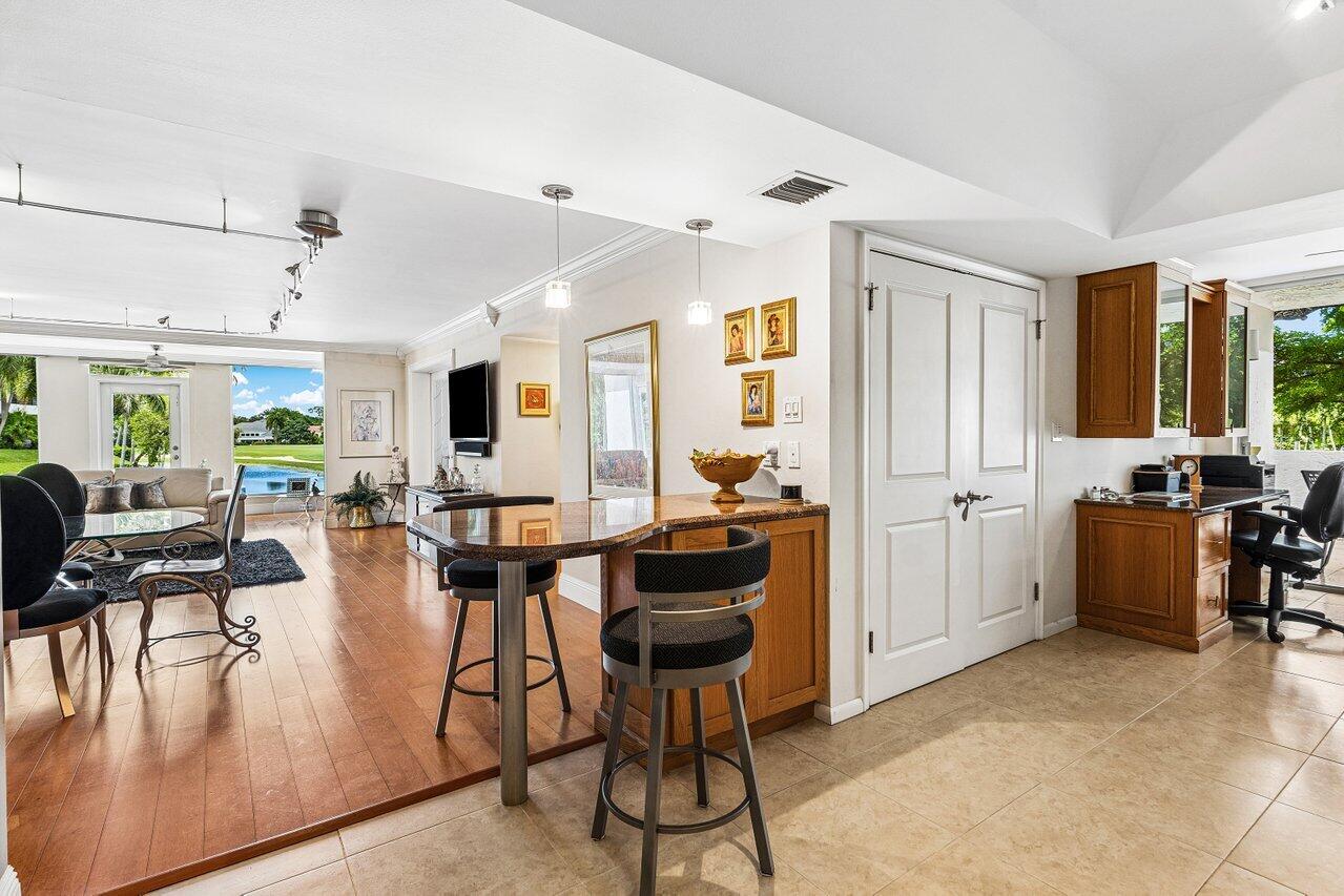 Open-plan living and dining area with a kitchen counter and views of a pool and golf course.