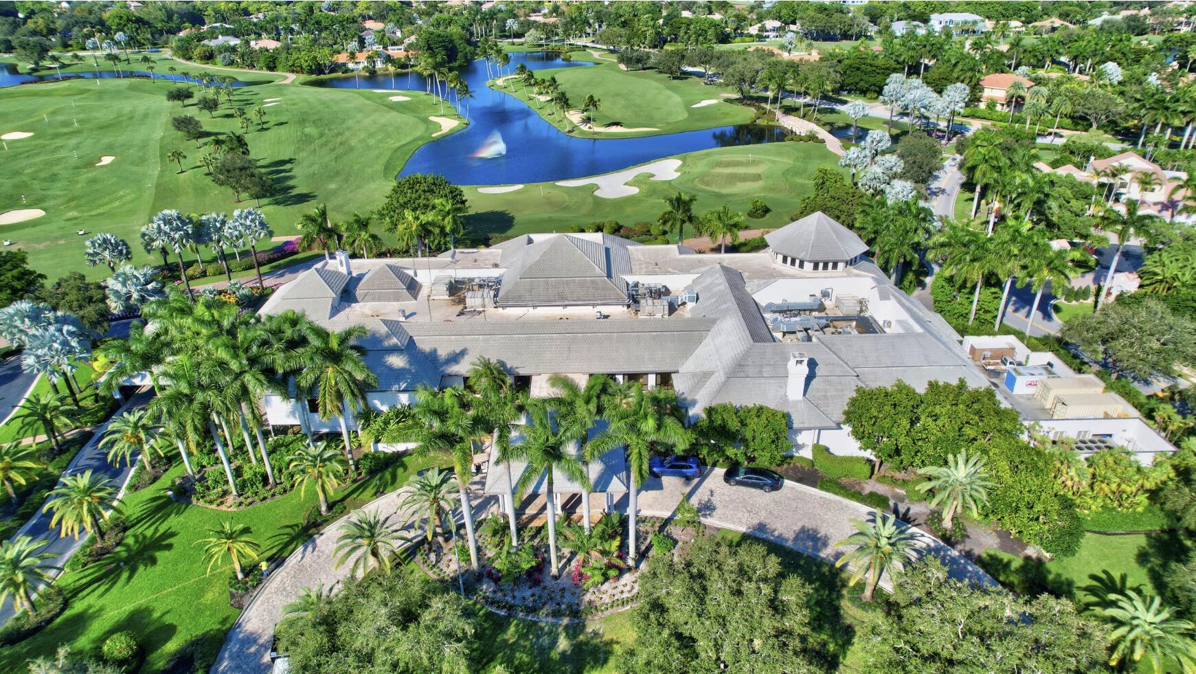 Aerial view of a palm-lined residence beside a golf course and pond.