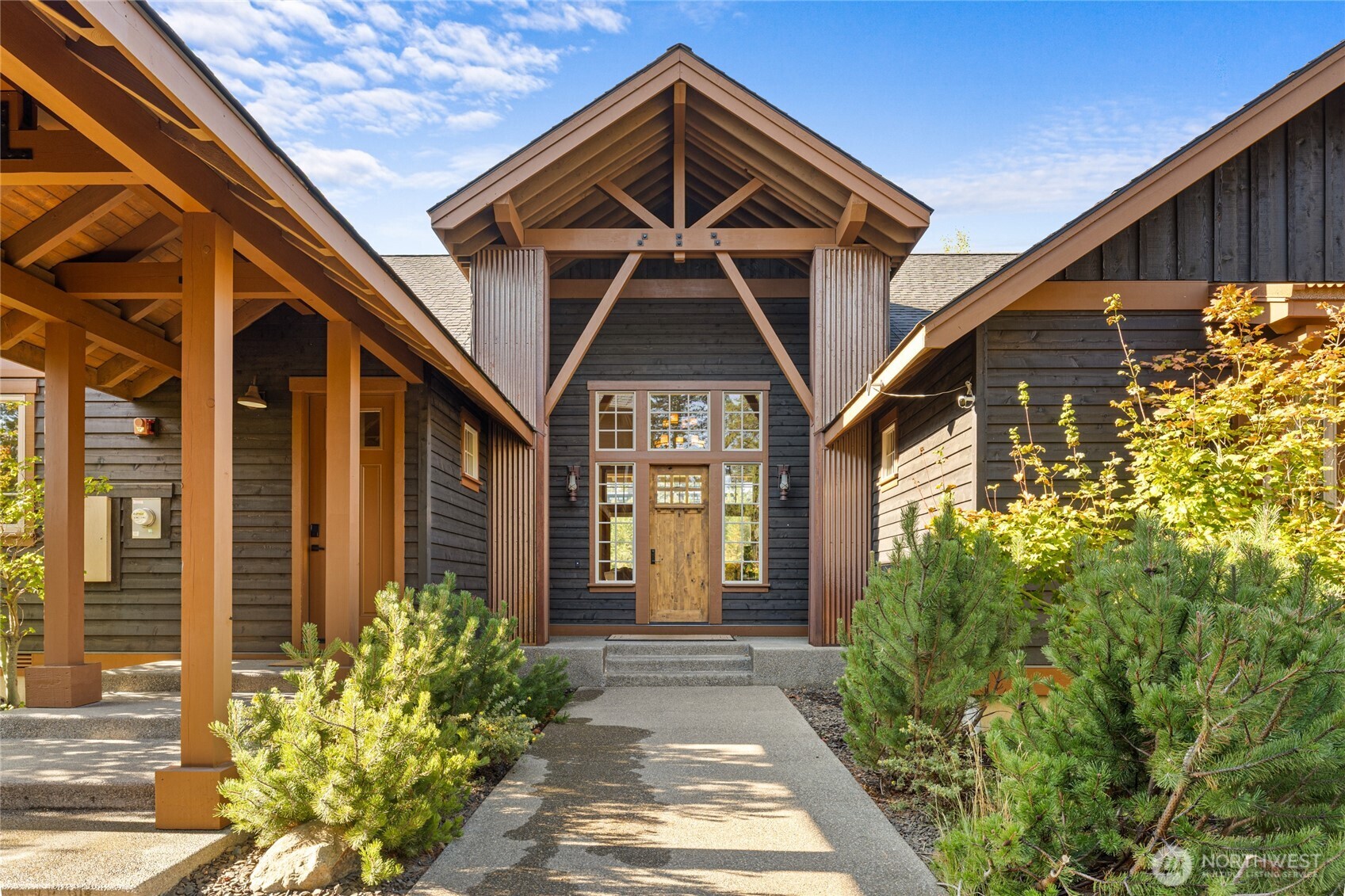 Dark wood home with a timber-framed gabled entrance and landscaped walkway.