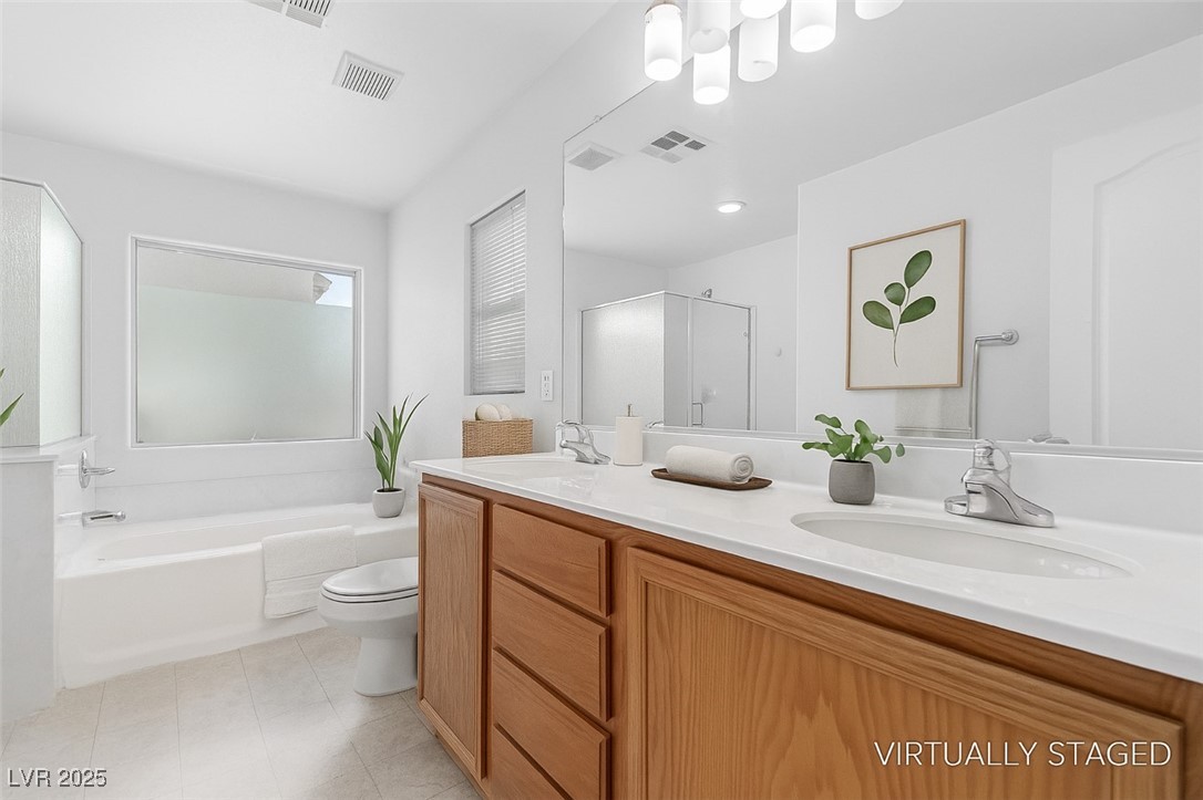 Bathroom with a long wood vanity, two sinks, bathtub, and glass-enclosed shower.