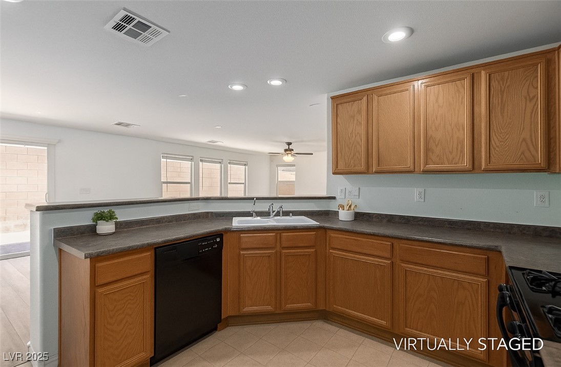 Kitchen with warm wood cabinetry, dark countertops, and a breakfast bar separating it from a bright adjoining room.