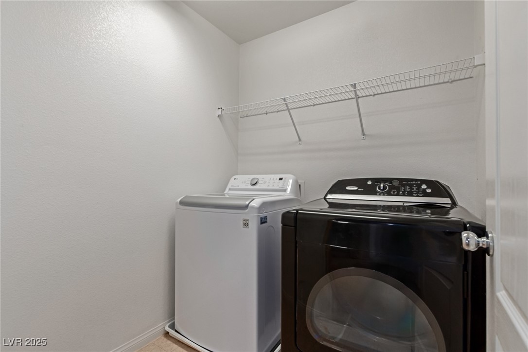 Laundry room with a white top-loading washer, black front-loading dryer, and wire shelf.