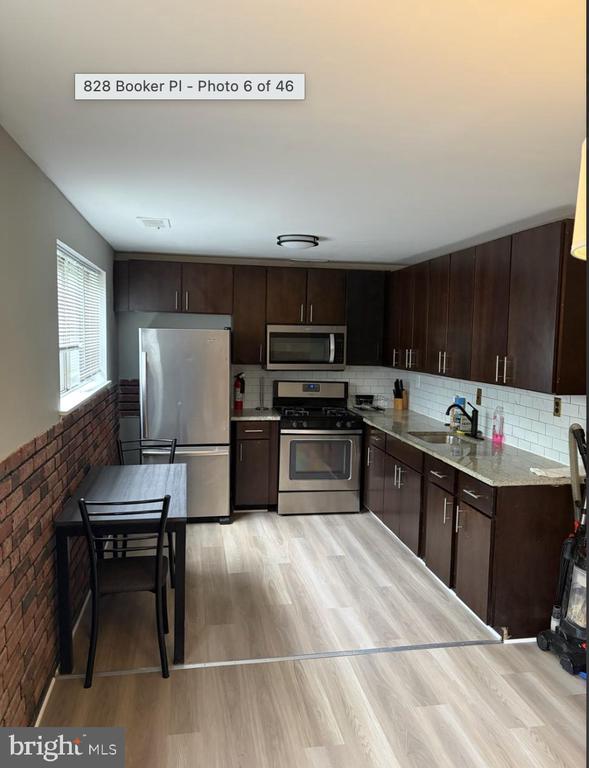 Kitchen with dark wood cabinets, stainless steel appliances, and a small table beside the window.