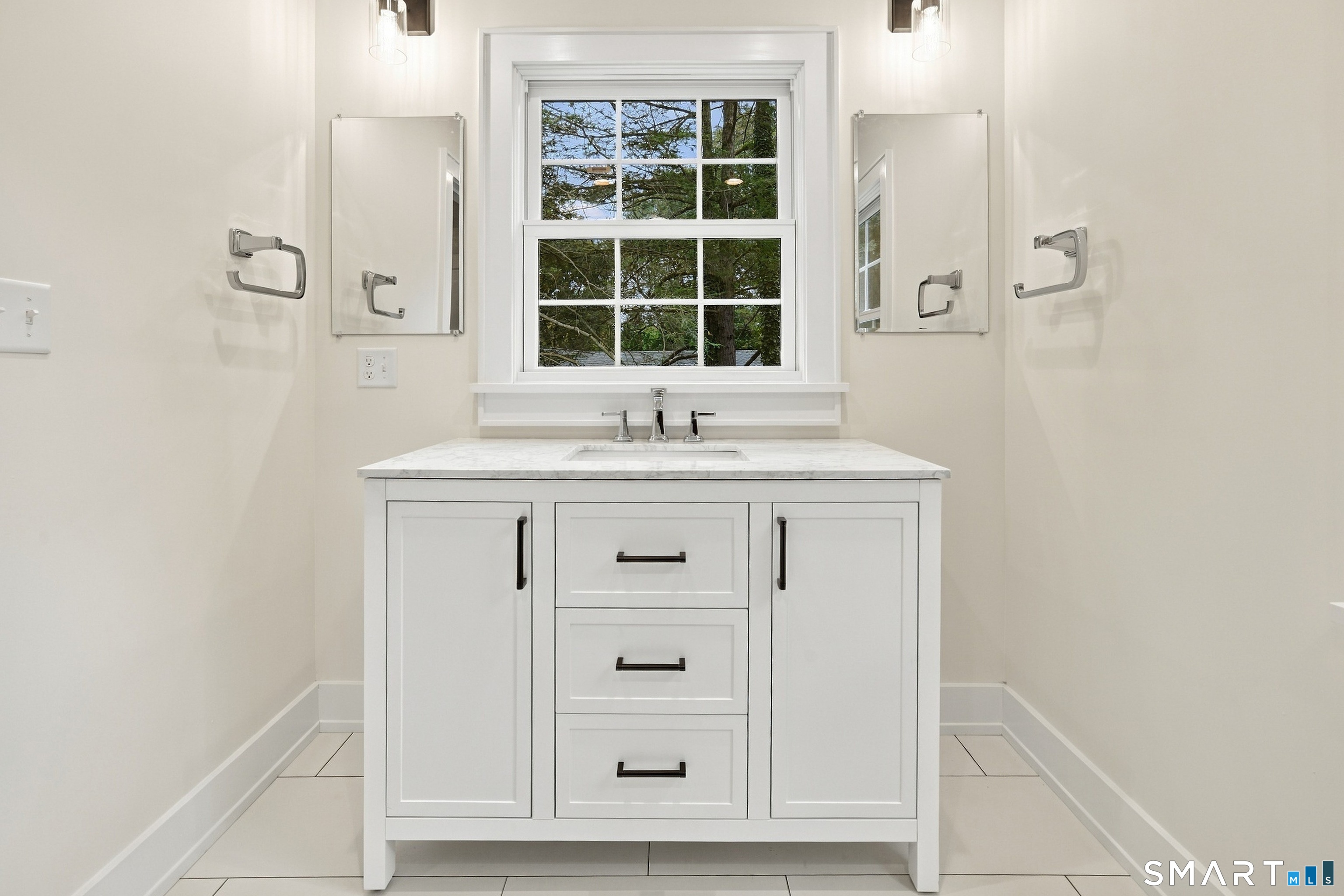Bright bathroom with a white marble-topped vanity beneath a large window.