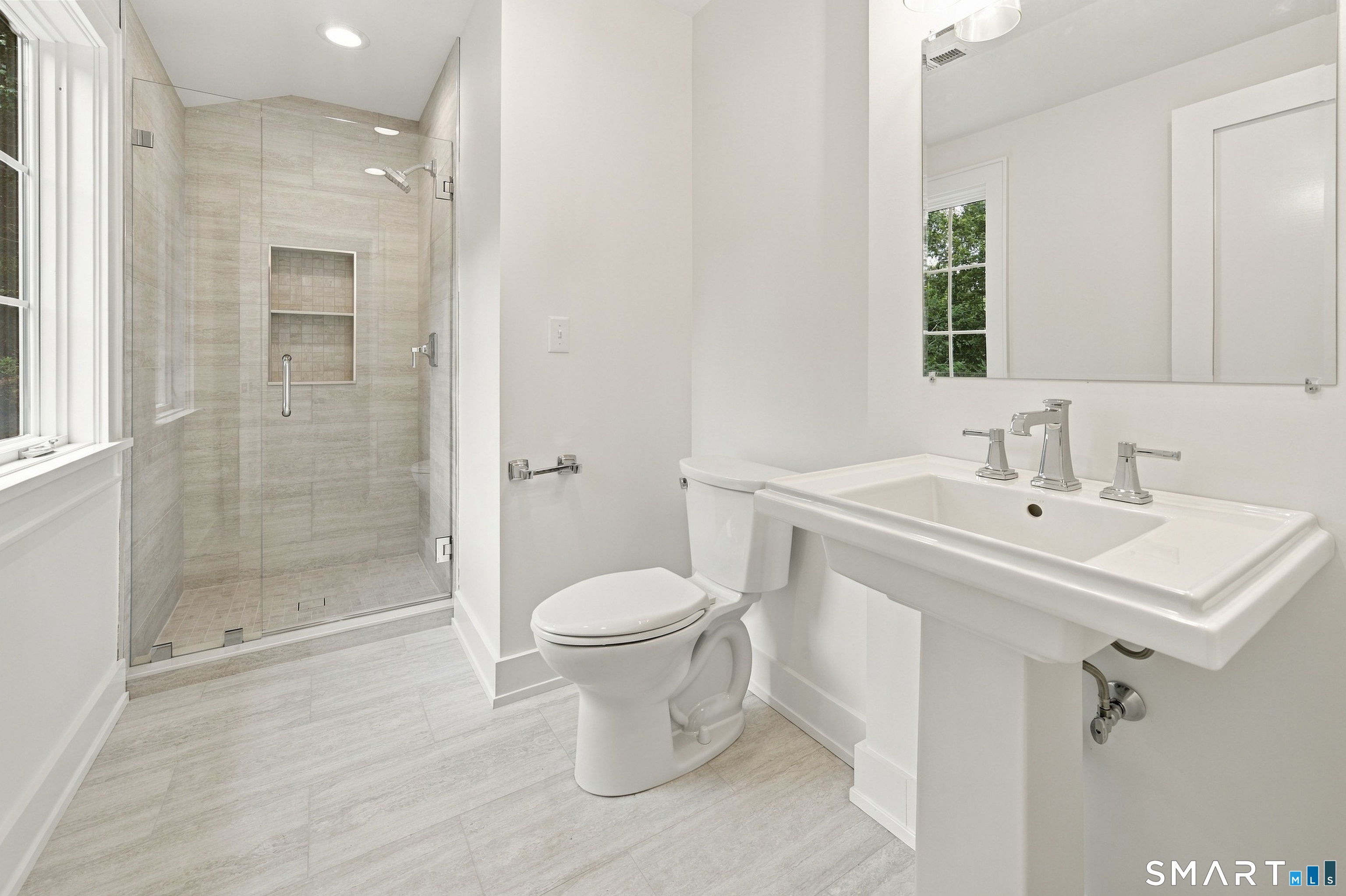 Bathroom with a glass-enclosed tiled shower, pedestal sink, and large mirror.
