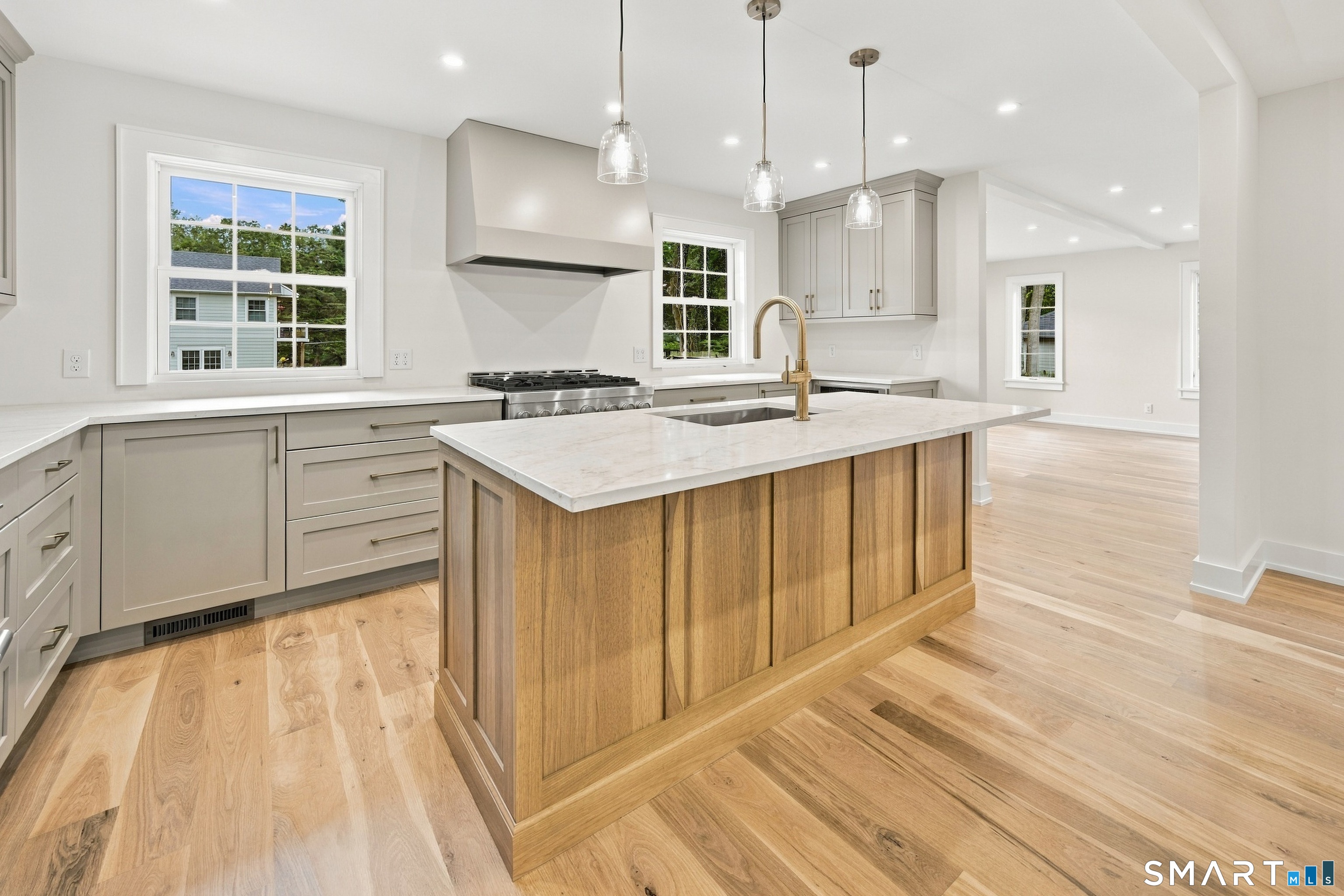 Kitchen with a large wood-paneled island, white countertops, and gold-tone faucet.