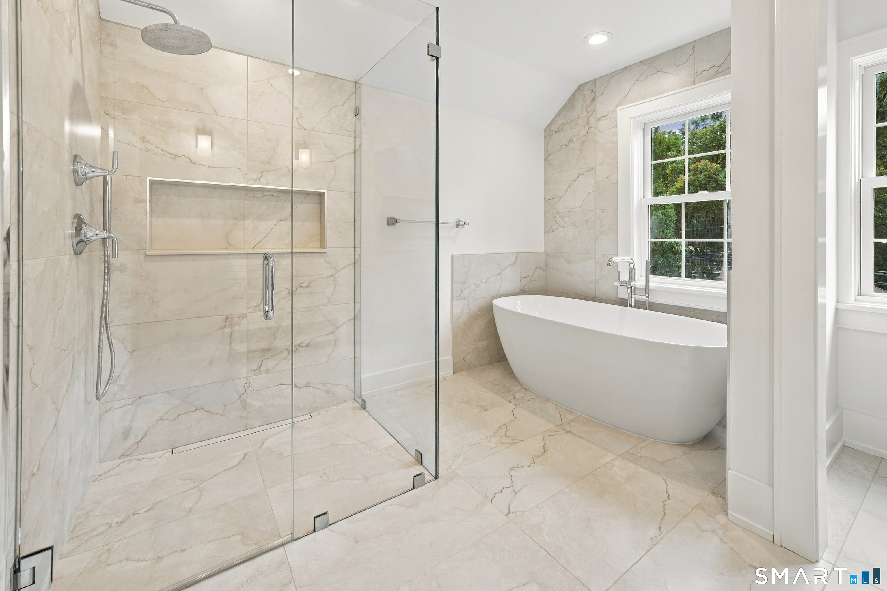 Bathroom with a glass walk-in shower and freestanding soaking tub beside tall windows.