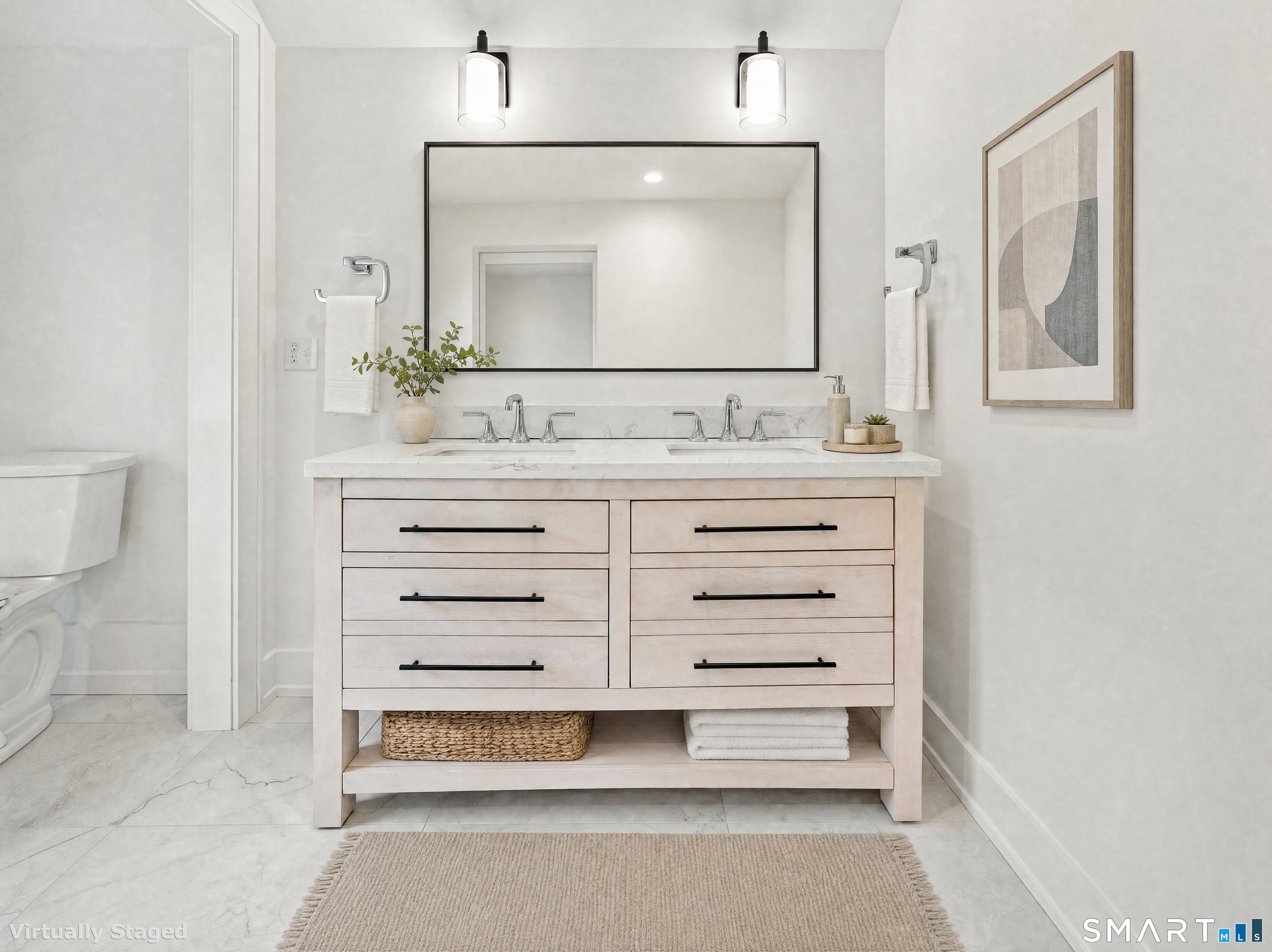 Bathroom with a pale wood double vanity, marble countertop, large mirror, and framed abstract art.