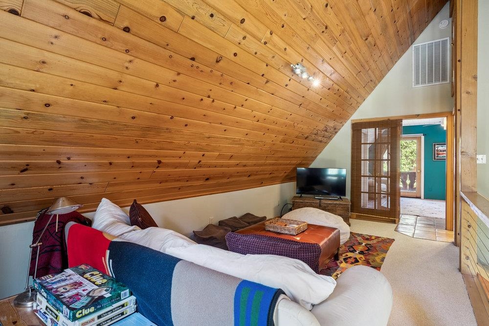Furnished living room with a white sectional beneath a dramatic knotty-pine vaulted ceiling.