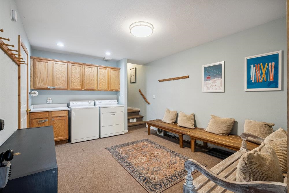 Laundry room with washer and dryer, wood cabinets, and a long cushioned bench.