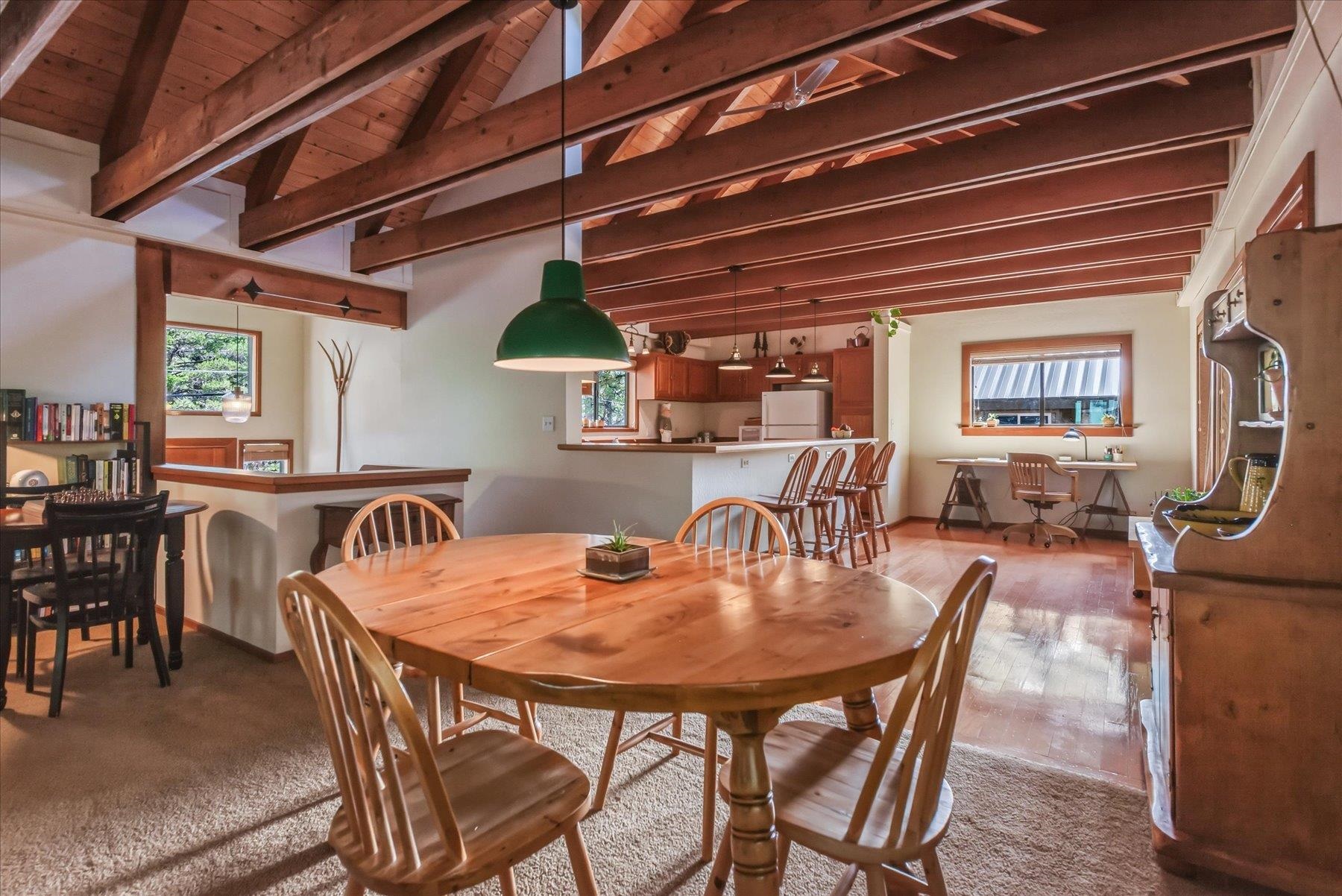 Open-plan dining room and kitchen with exposed wood beams and a large wooden dining table.