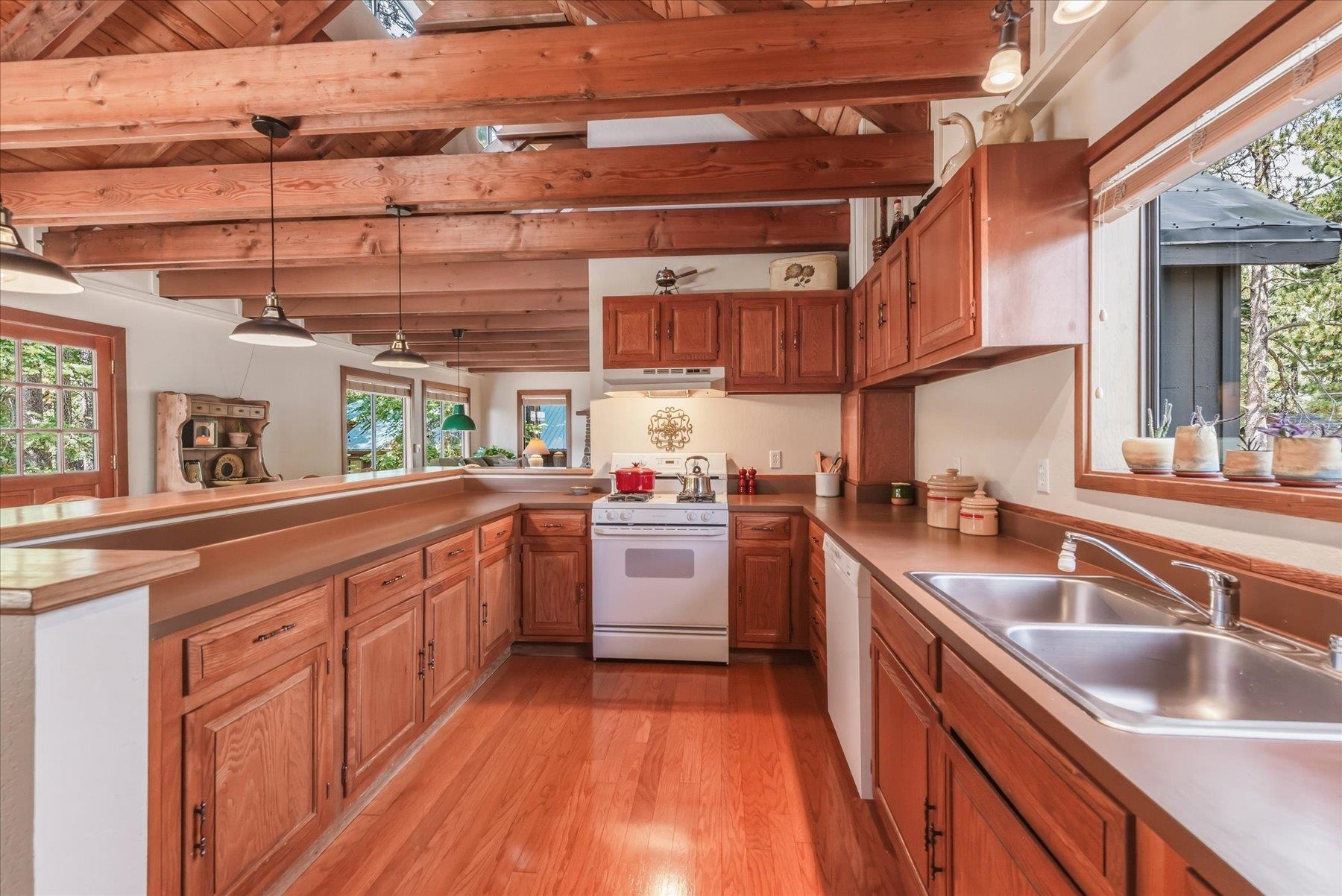 Kitchen with reddish wood cabinets, exposed ceiling beams, and a double-basin sink.