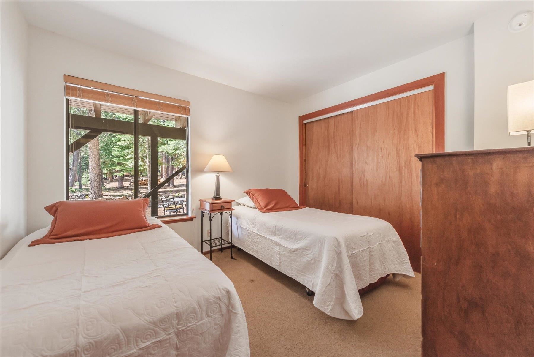 Bedroom with two twin beds and a window overlooking trees.