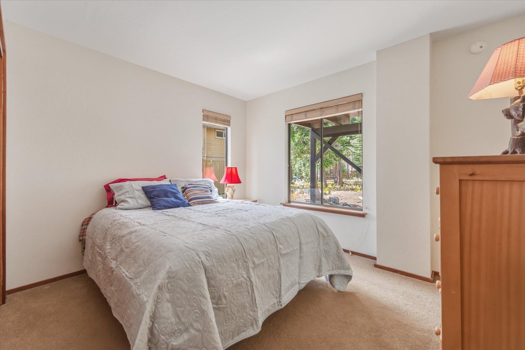 Bedroom with a large quilt-covered bed and windows overlooking trees