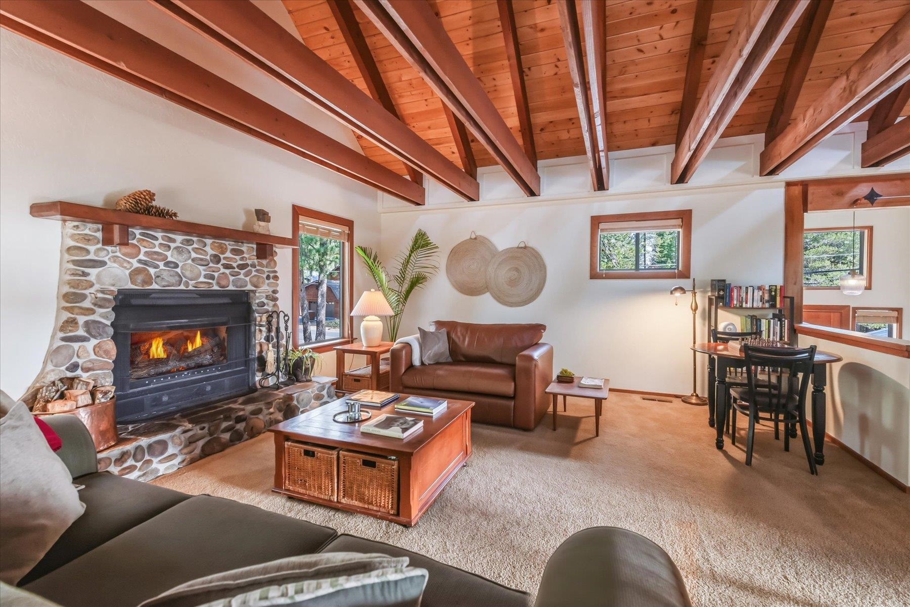 Living room with a stone fireplace, vaulted wood ceiling, and leather seating.