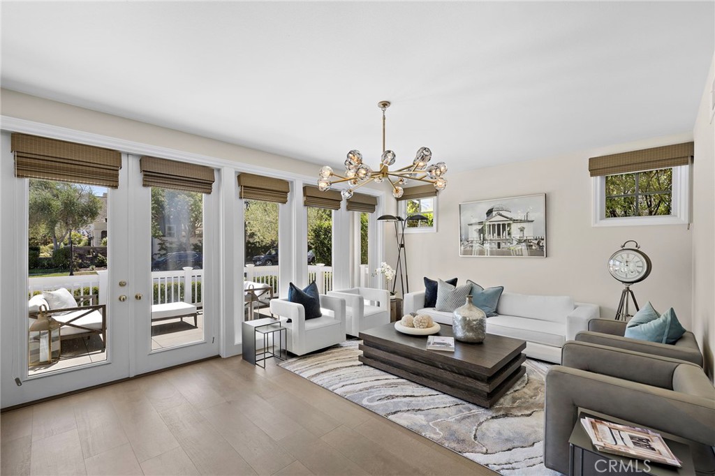 Staged living room with white seating, a dark coffee table, and glass doors opening to a patio.