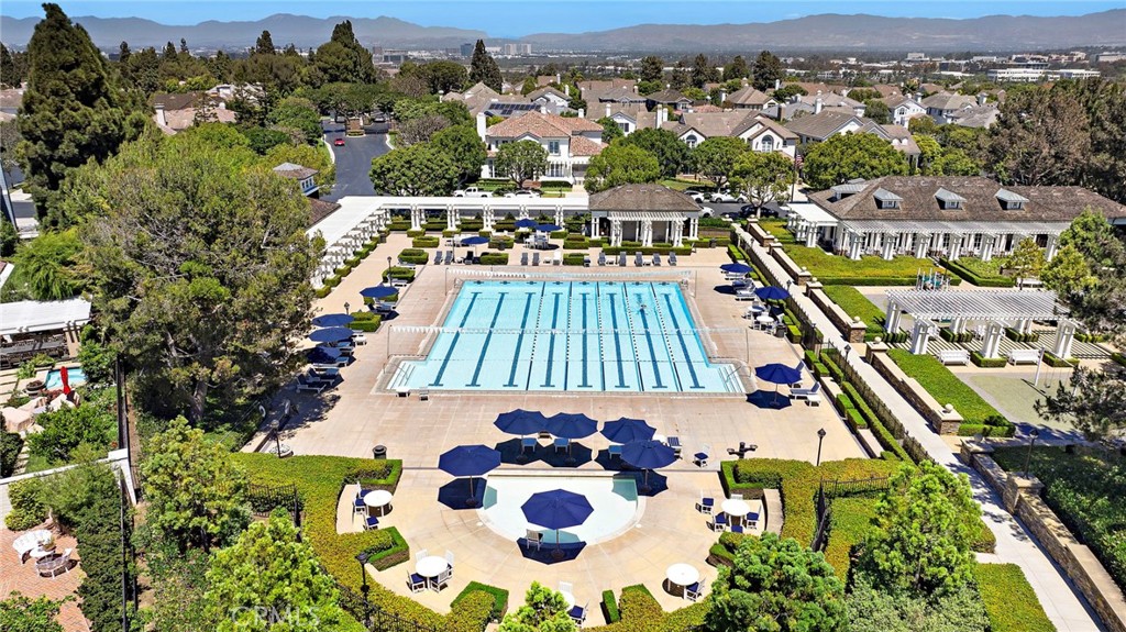 Aerial view of a lap pool and landscaped pool deck with blue umbrellas.