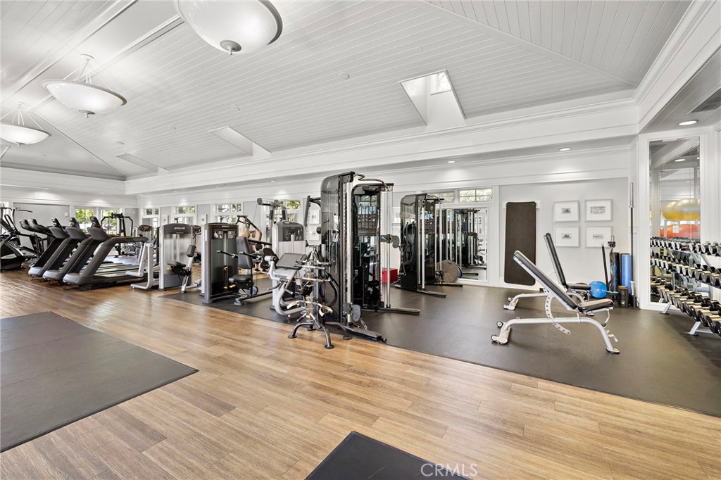 Gym with rows of exercise machines, mirrored walls, and wood-look flooring.