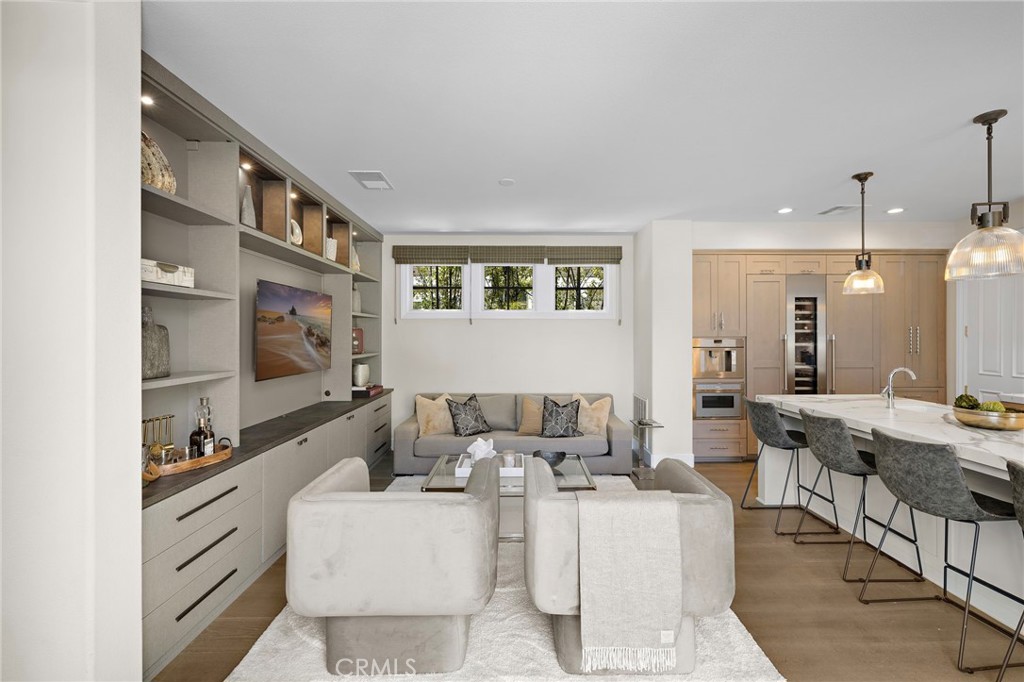 Open-plan living room and kitchen with built-in shelving, a gray sofa, and a marble island.