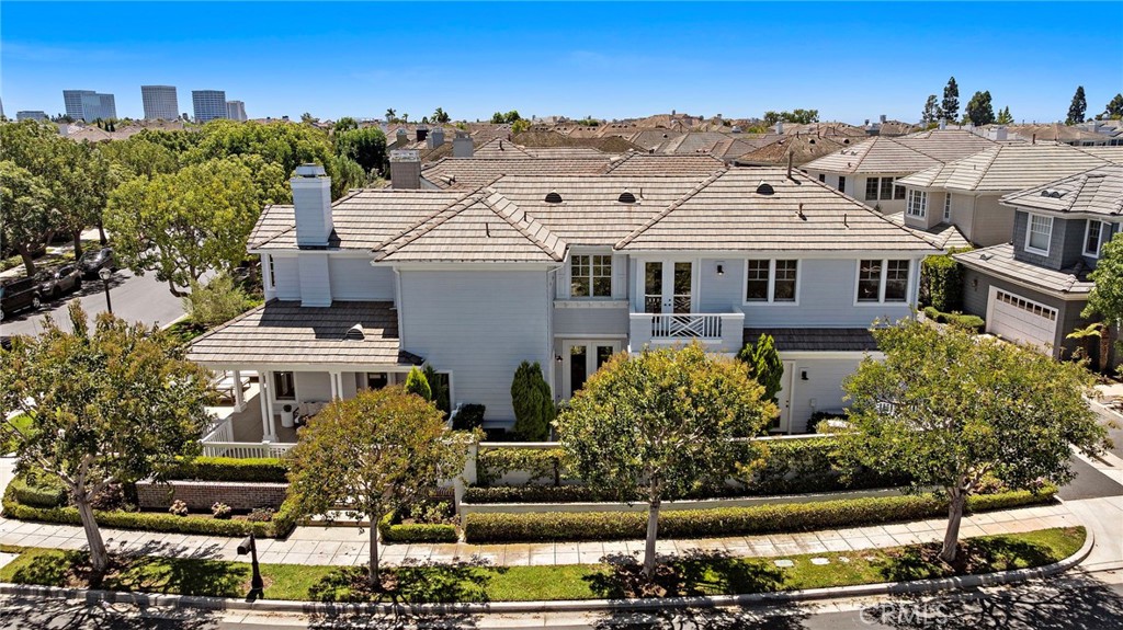 Aerial view of a two-story Newport Beach home with a tan tile roof and landscaped corner lot.