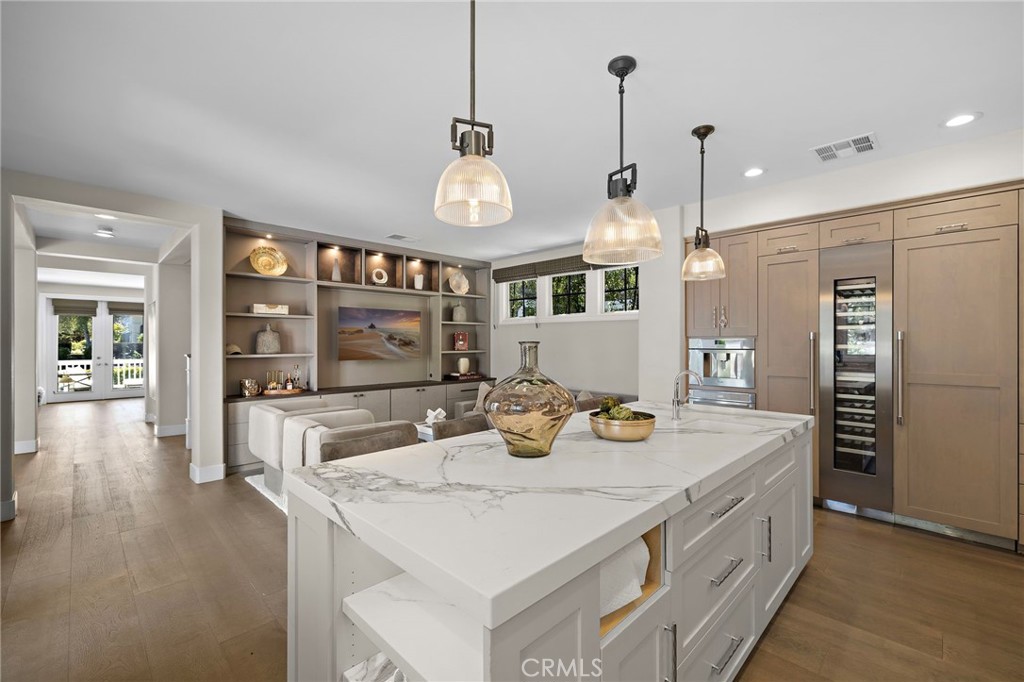 Modern kitchen with a large marble island, light wood cabinetry, and pendant lights.