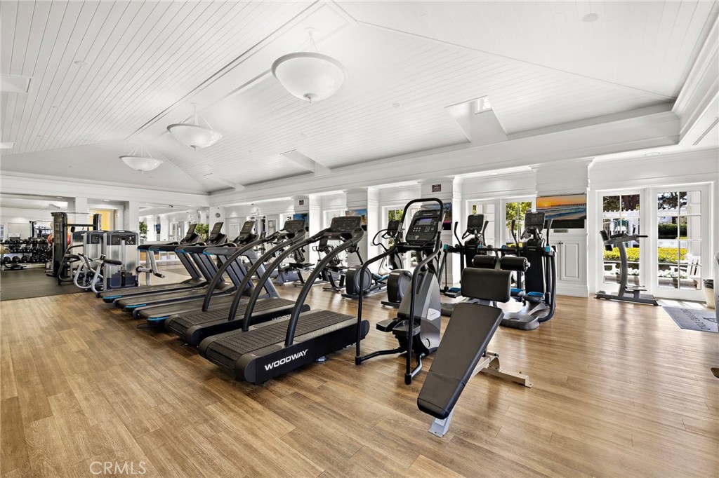 Fitness room with rows of treadmills, weight equipment, and large windows.