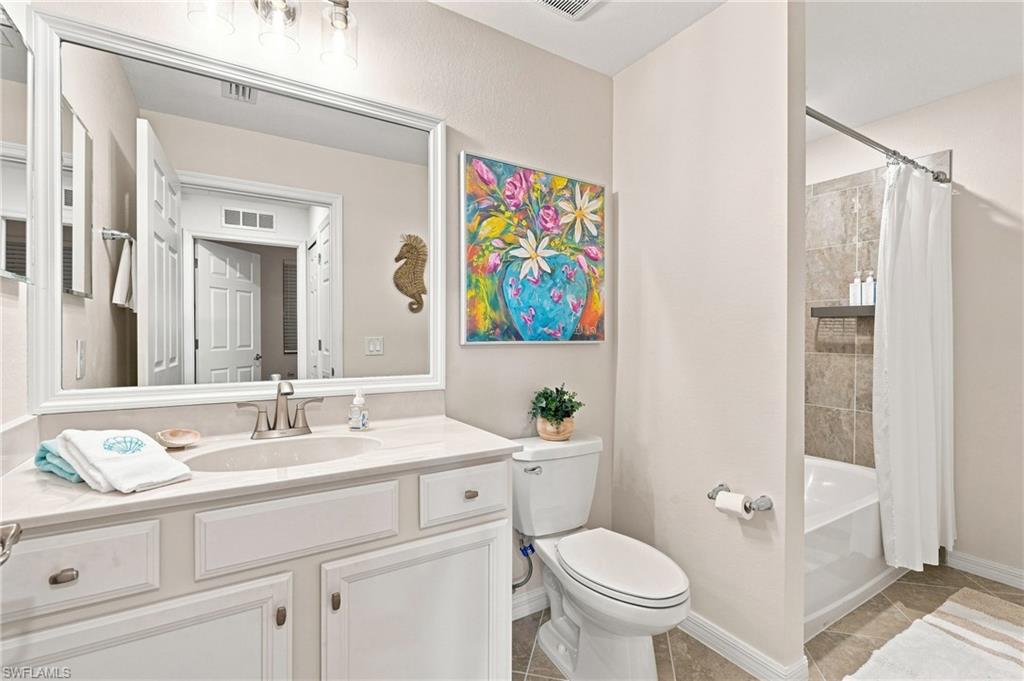 Bathroom with a white vanity, large mirror, and tiled tub-shower with a white curtain.