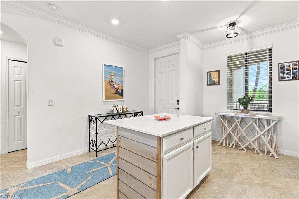Bright kitchen with a white island, blue runner, and window overlooking palm trees.