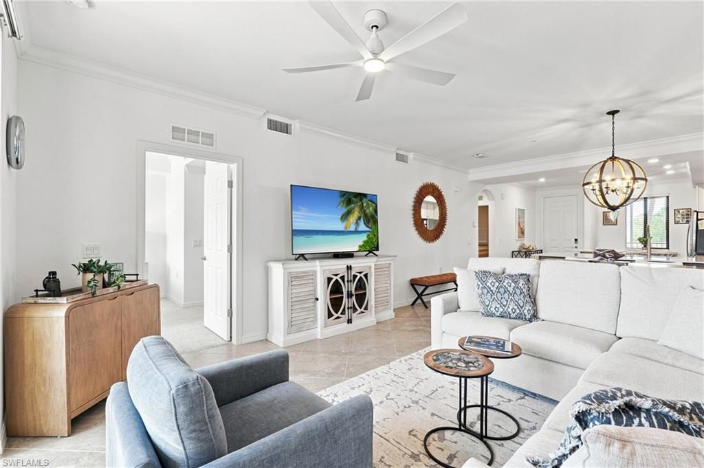 Furnished living room with a white sofa, gray armchair, and TV console.