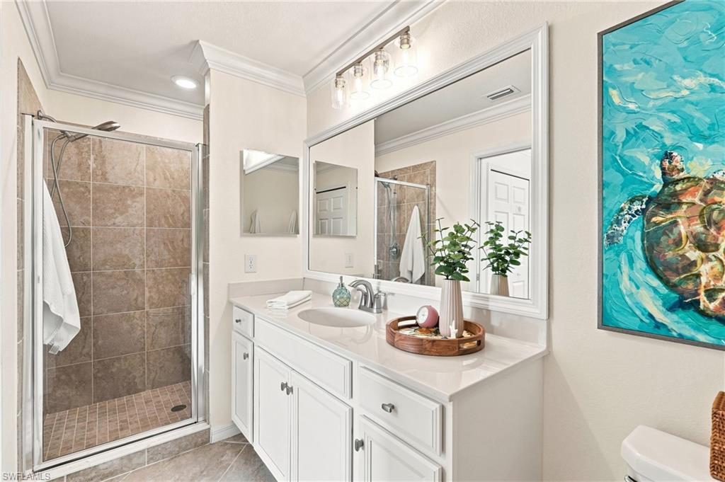 Bathroom with a white vanity, large mirror, tiled glass shower, and turquoise sea turtle artwork.