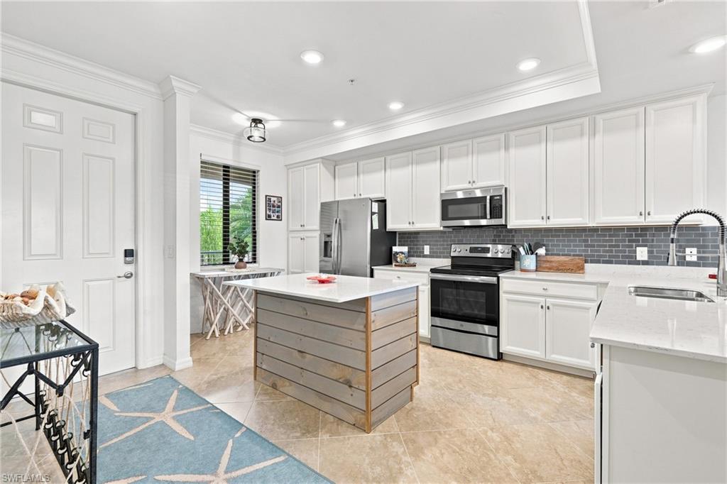 Bright kitchen with white cabinets, stainless appliances, and a wood-paneled island.