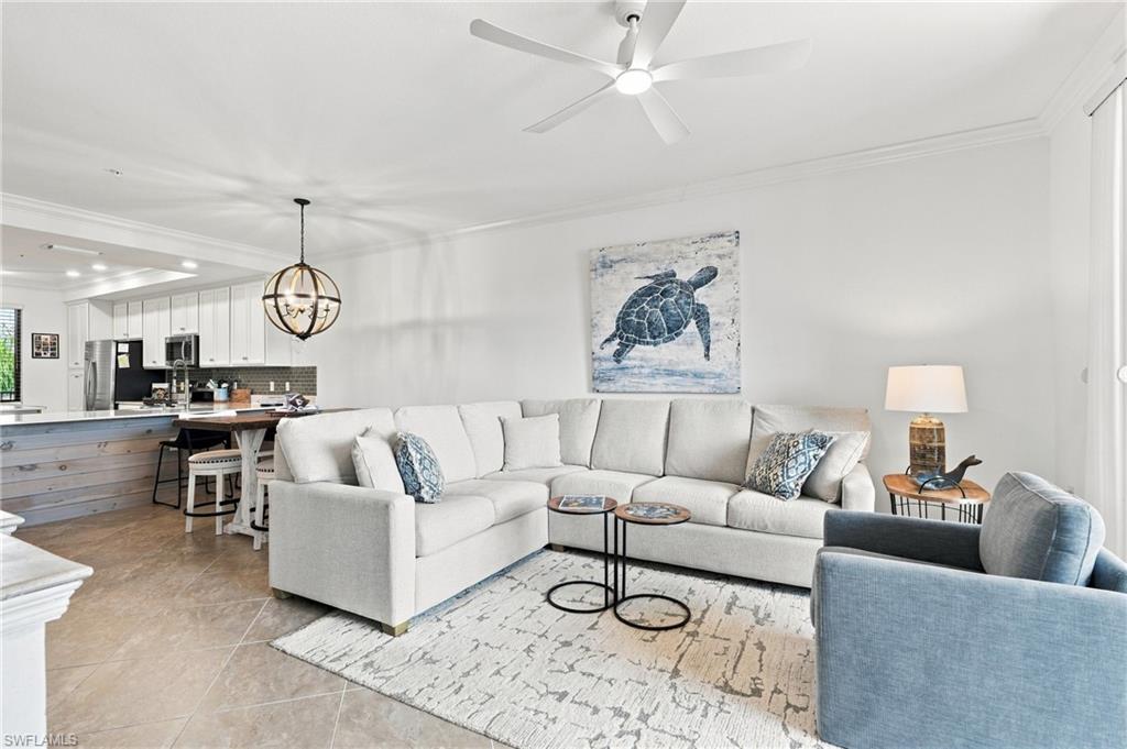 Open-plan living room with a white sectional, blue armchair, turtle artwork, and kitchen island.