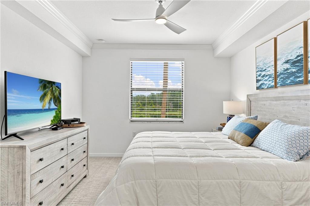 Bright bedroom with a large bed, light wood dresser, ceiling fan, and window with blinds.