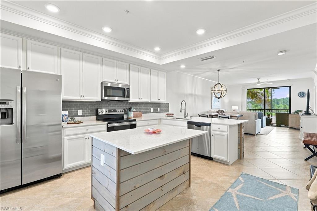Open-plan kitchen with a large wood-paneled island, white cabinets, and stainless steel appliances.