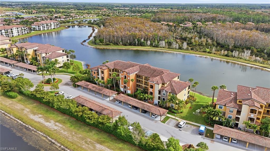 Aerial view of Treviso Bay condos beside a lake, with red tile roofs and covered carports.