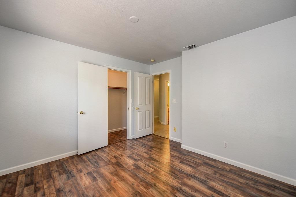 Empty room with wood-look flooring and an open closet and doorway.