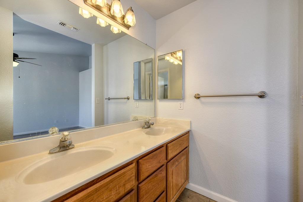 Bathroom with a double-sink vanity, large mirror, and wood cabinetry.