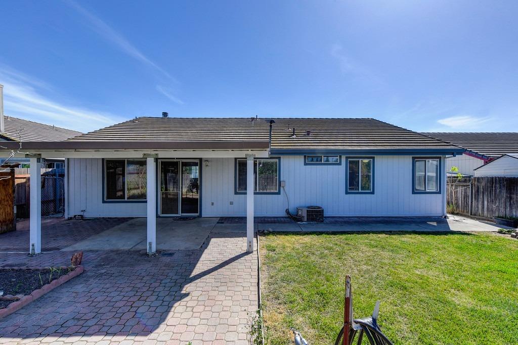 Rear of a light blue single-story home with a covered patio and small lawn.