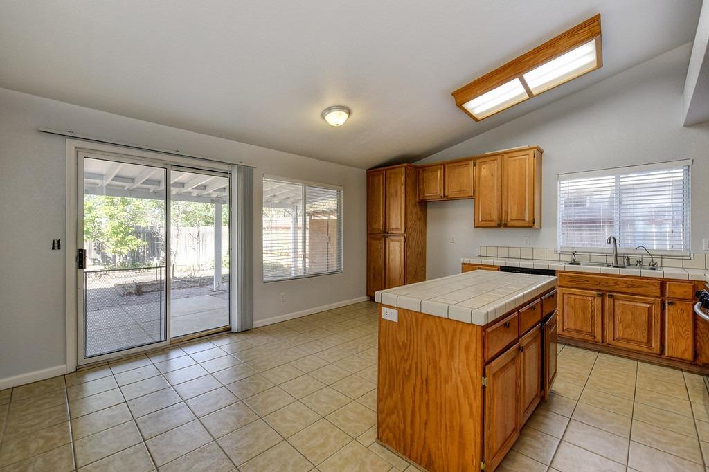 Kitchen with wood cabinets, a tiled island, and sliding glass doors to a covered patio.