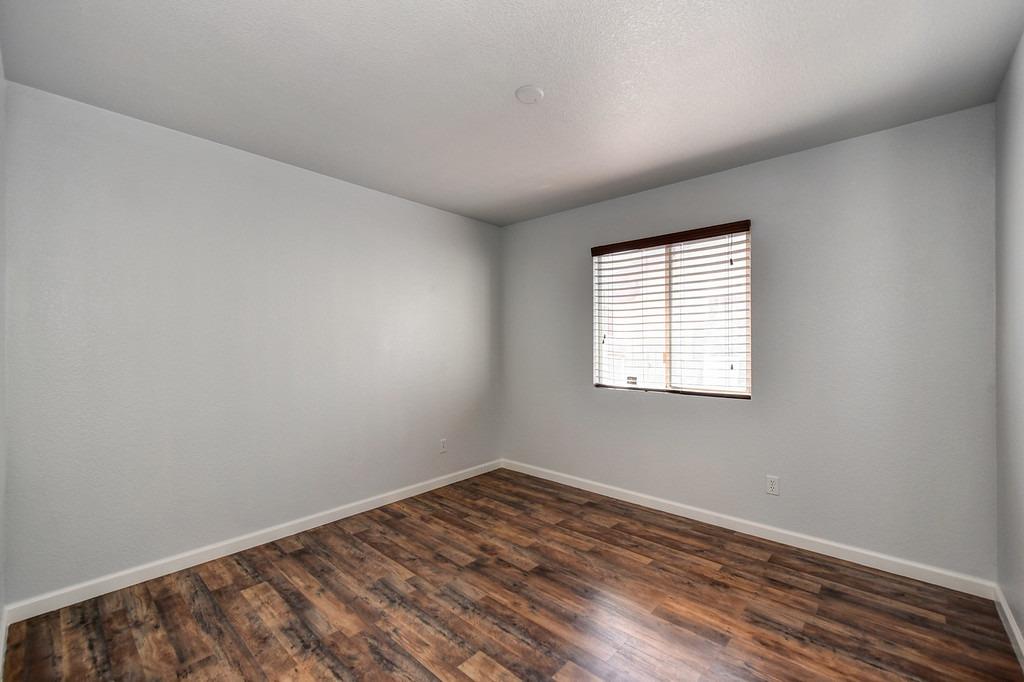 Empty bedroom with dark plank flooring and a window with blinds.