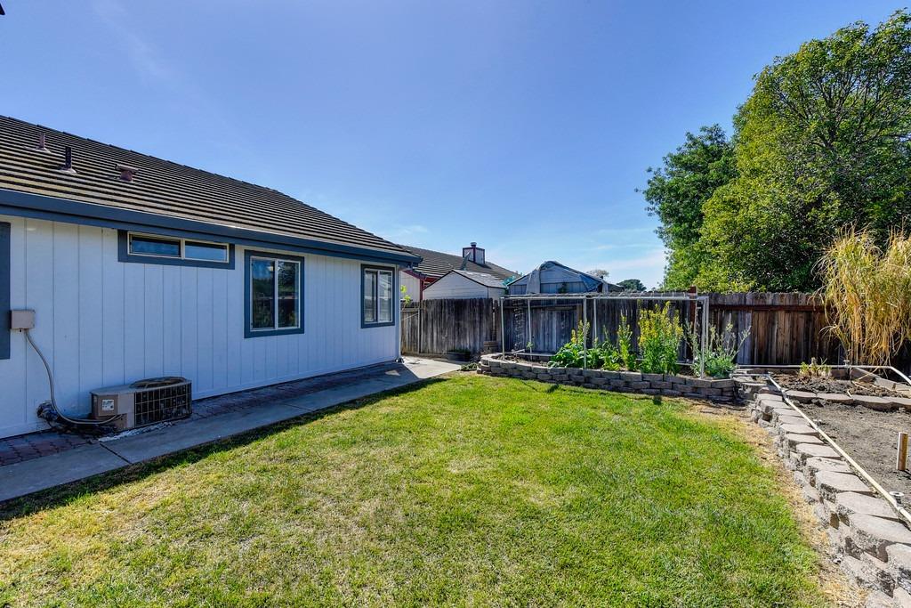 Backyard with a broad lawn, raised garden beds, and a wooden fence.