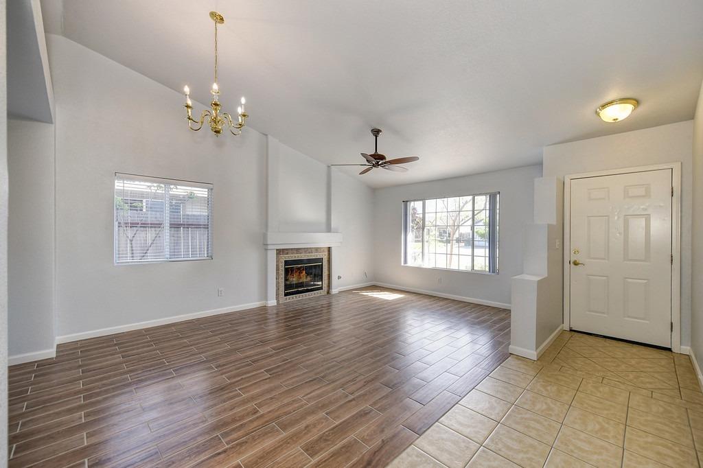 Vacant living room with a fireplace, wood-look flooring, and a tiled entry.